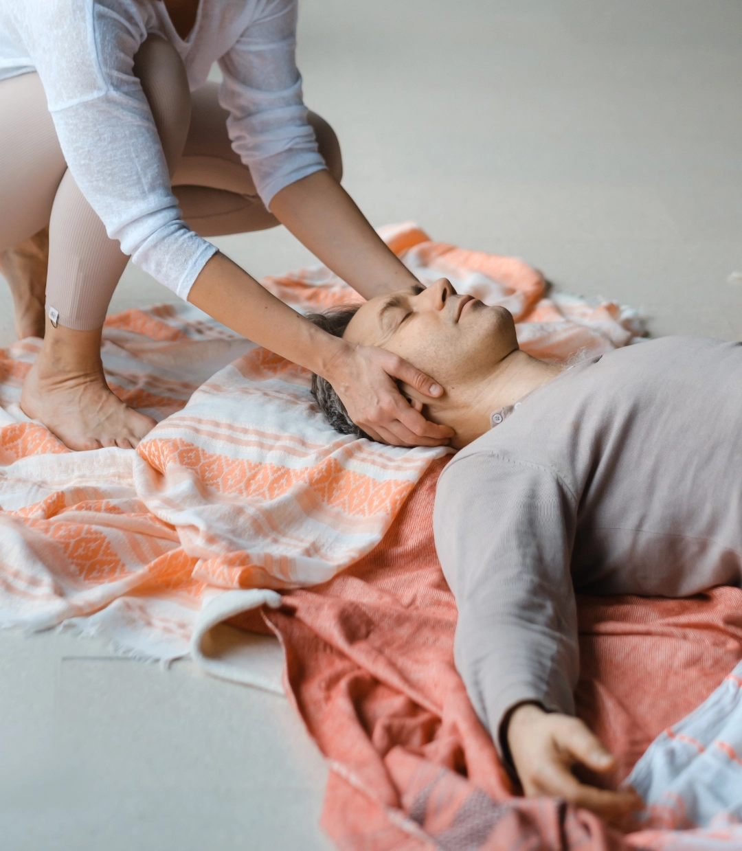 Une femme pose délicatement ses mains pour un massage cranien sur un homme MCM METAMORPHOSE